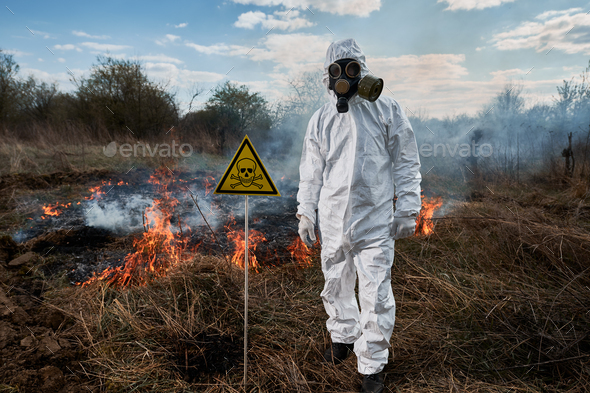 Firefighter ecologist in gas mask working in field with wildfire. Stock ...