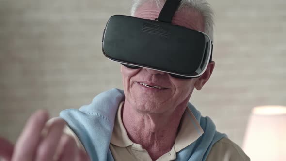 Old Man in VR Goggles Touching Something in Air alt
