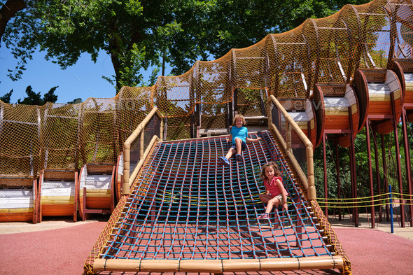 Two children enjoy an outdoor playground where they develop physical skills.