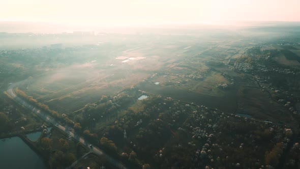 Aerial View of an Asphalt Road Between Agricultural Fields and a Lake alt