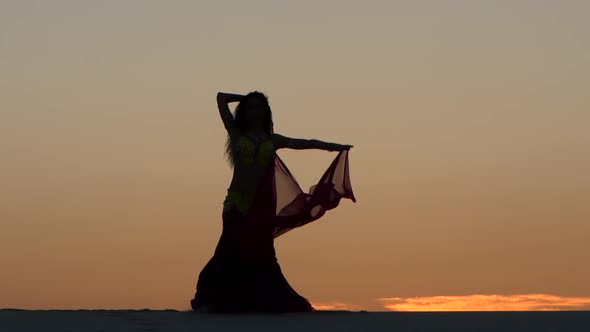 Girl Gracefully Dances with a Veil of Hands Against a Sunset. Silhouette alt