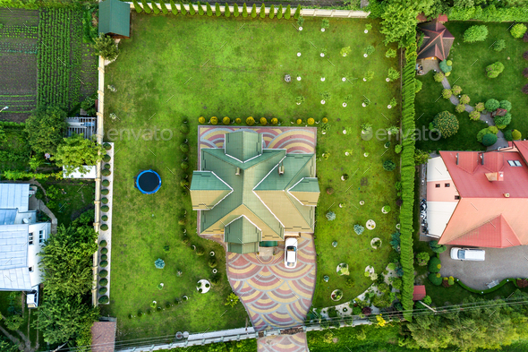 Aerial top view of house shingle roof and a car on paved yard with green grass lawn