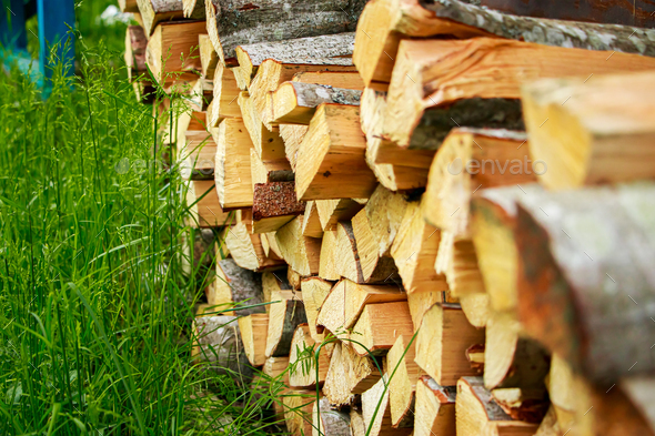 Stack of chopped firewood. Eco-friendly bio fuel. Woodpile near village house.