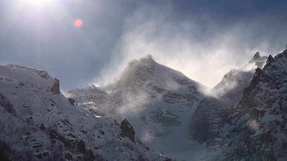 Timelapse on a Telephoto Lens of Snowcapped Peaks of High Mountains with Snow Blowing From the Peaks alt