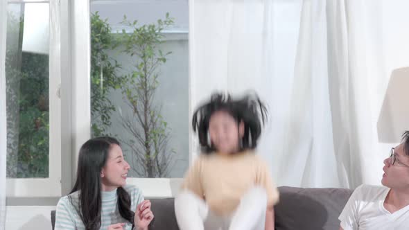 Daughter jumps on the sofa show her parent. Asian family spend time together