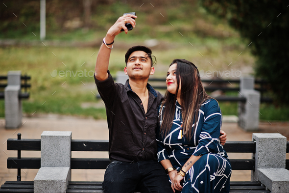 Rear view of a happy young couple sitting on a park bench, young woman  looking to camera over the shoulder while her boyfriend is kissing her  Stock Photo | Adobe Stock