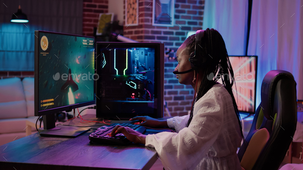 African american gamer girl using pc gaming setup playing multiplayer space shooter simulation