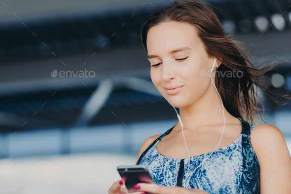 Woman holds smart phone, texts feedback, checks email box, listens music in player.