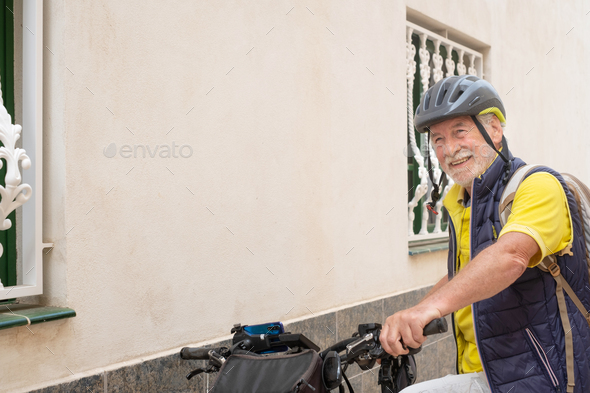 Smiling cyclist elderly man in urban street wearing helmet before running with his electro bicycle
