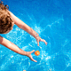 Baby swims in a pool trying to reach a toy in the water, top view in summer. - PhotoDune Item for Sale