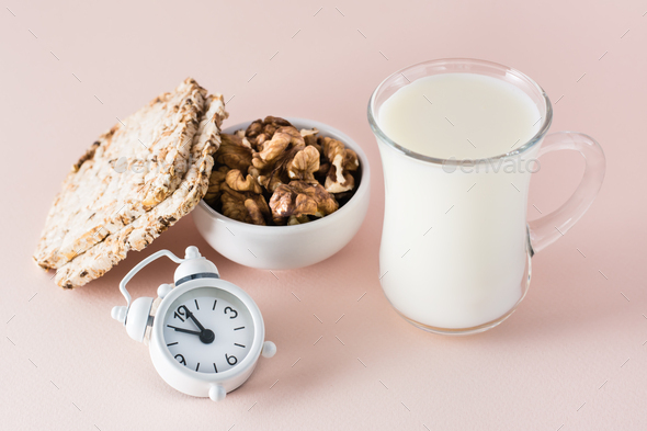 Good sleep. Foods for good sleep - milk, walnuts, crispbread and alarm clock on pink background
