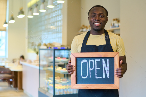Waiter with open sign welcoming guests to cafe
