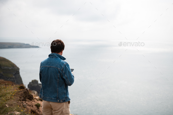 Man is standing on edge of the cliff on Irish sea