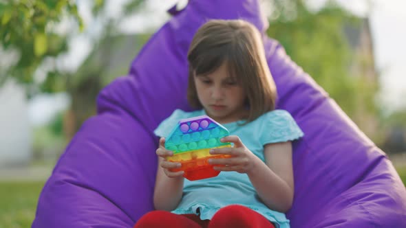 Little Girl Squeezing Colorid Anti-stress Toy Child is Playing a Popular Game With Buttons