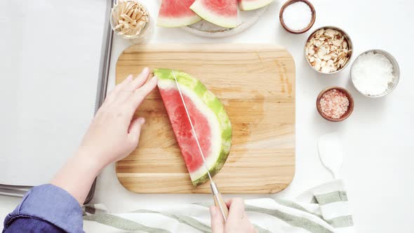 Slicing watermelon in cubes for preparing watermelon appetizers dipped in chocolate and sprinked wit alt