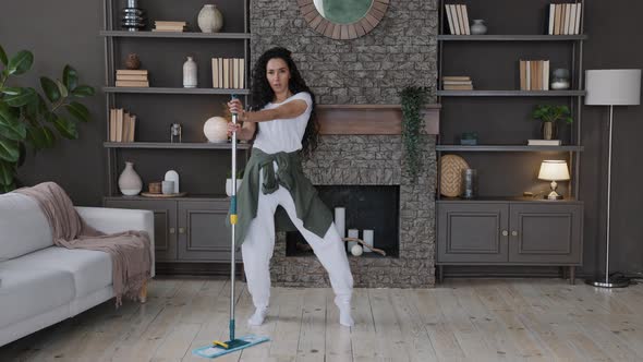 Energetic Hispanic Woman Housewife Cleans Living Room Sings Song Using Mop As Microphone Imagines alt