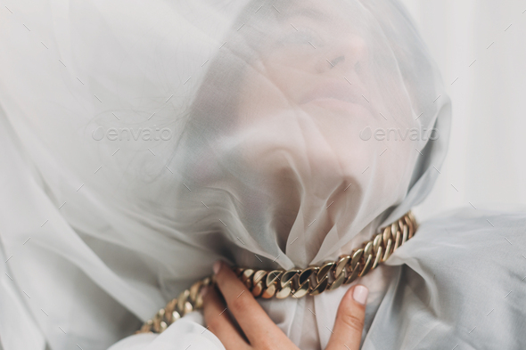Portrait of female covered with light fabric and hand on neck. Mental break and social pressure