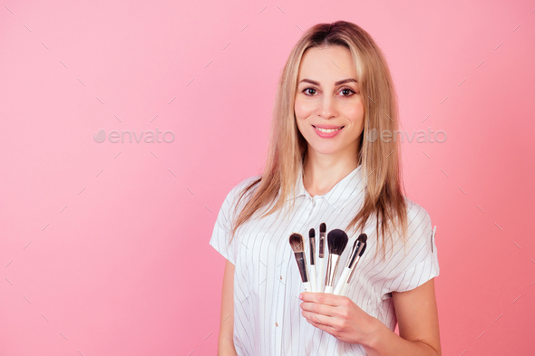 attractive blond visagiste make-up artist woman holding a makeup many brushes