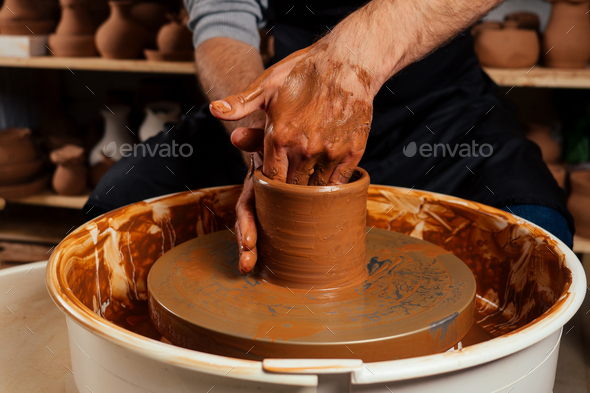 potter professional happy man working with brown clay in workshop . Stock  Photo by yurakrasil