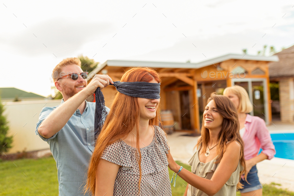 Man placing blindfold over woman\'s eyes while playing blind man\'s buff