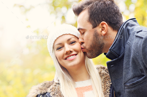 Young romantic couple kissing in the park in autumn Stock Photo by macniak