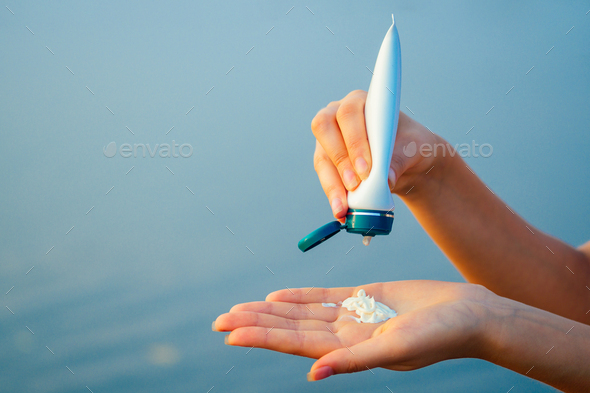 protective sun cream on the ocean in the hands of a girl - Stock Photo - Images