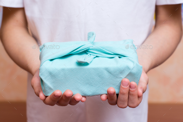 Furoshiki eco-friendly gift wrapped in cloth in children\'s hands. Zero waste.