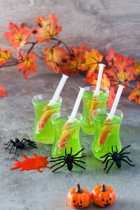 Halloween cocktails. Syringes with blood in glasses with green lemonade