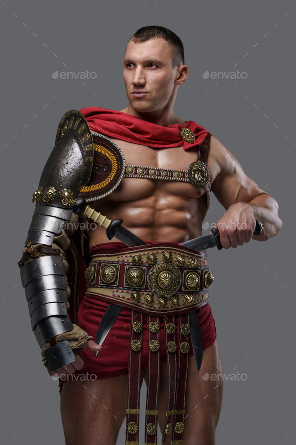 Muscular colosseum fighter holding twin swords against grey background ...