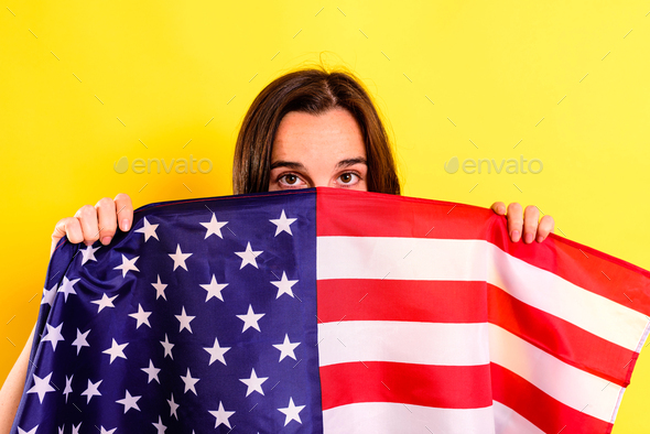 Young embarrassed woman covers herself with an American flag
