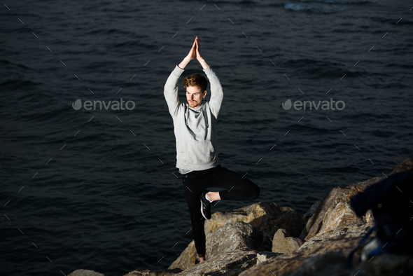 Young redhead practicing yoga, Vriksasana tree posture - Stock Photo - Images