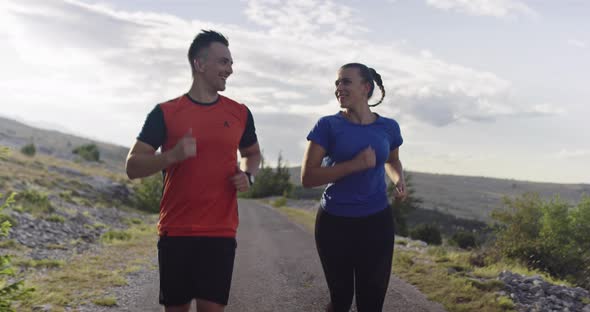 Tracking Slow Motion Shot of Sportive Couple Jogging Outdoors in the Morning Trail Running alt