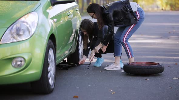 The Two Women Lifted the Car with a Jack to Replace a Punctured Tire alt