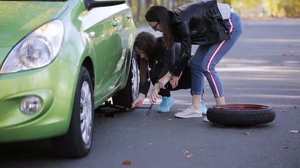 The Two Women Lifted the Car with a Jack to Replace a Punctured Tire