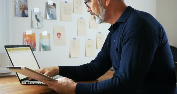 Man using laptop and digital tablet at home 4k alt