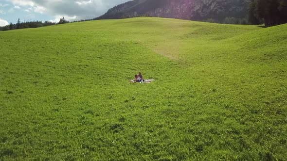 Couple on blanket in green field, Alta Badia, Italy