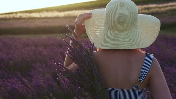Cinematic Footage of Woman Stands with Her Back Holds a Bouquet of Lavender and Slowly Touches Her alt