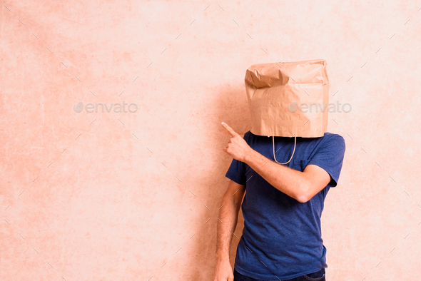 Funny man points his finger into empty space, with a bag covering his head.
