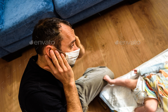 Novice father changing the smelly diaper of a baby, wearing a mask for ...