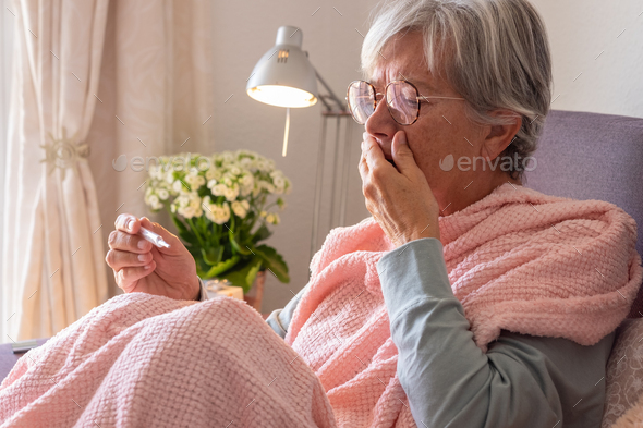 Suffering elderly adult caucasian woman with cough and fever as seasonal flu or pollen allergy