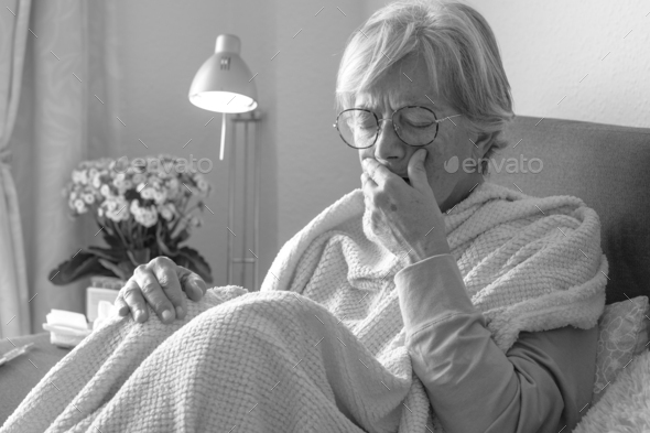 Suffering elderly adult caucasian woman with cough and fever as seasonal flu or pollen allergy