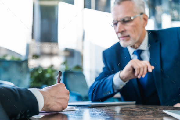 Businessman signing agreement, senior man in suit with company contract