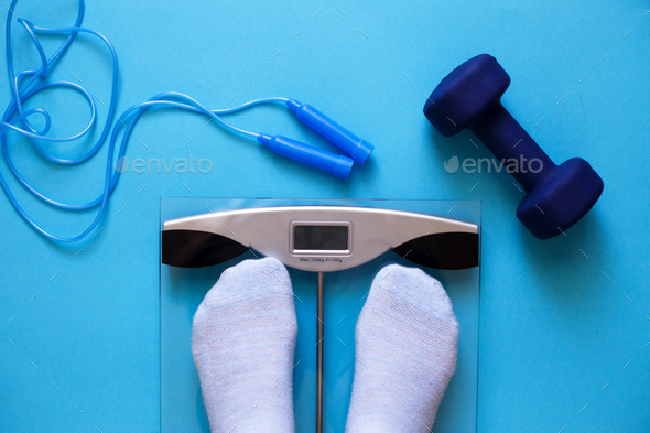 Woman measures her weight on scale on a blue background