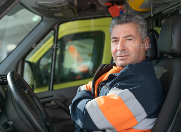 photo of a middle-aged ambulance driver with white hair with his arms crossed in the driver\'s seat.