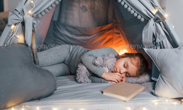 Sleep time. Cute little girl playing in the tent that is in the domestic room