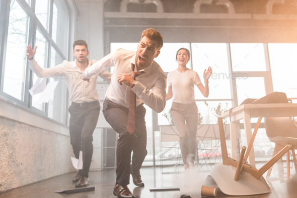 scared businesspeople running and screaming in office with smoke