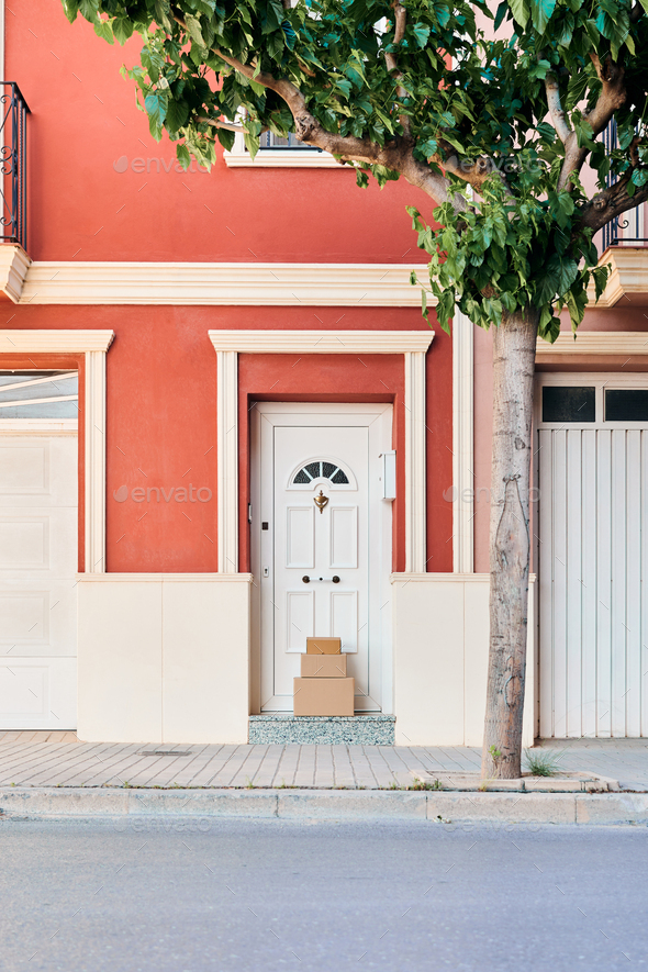 Facade of an orangecolored house with carton boxes on the door Stock