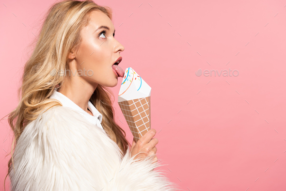 side view of beautiful sexy blonde woman in white faux fur jacket licking decorative ice cream