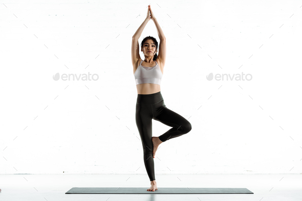 Happy and relaxed fitness girl, sitting on rubber mat doing yoga