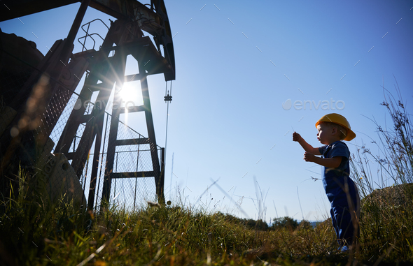 Kid guy standing near petroleum pump rig.